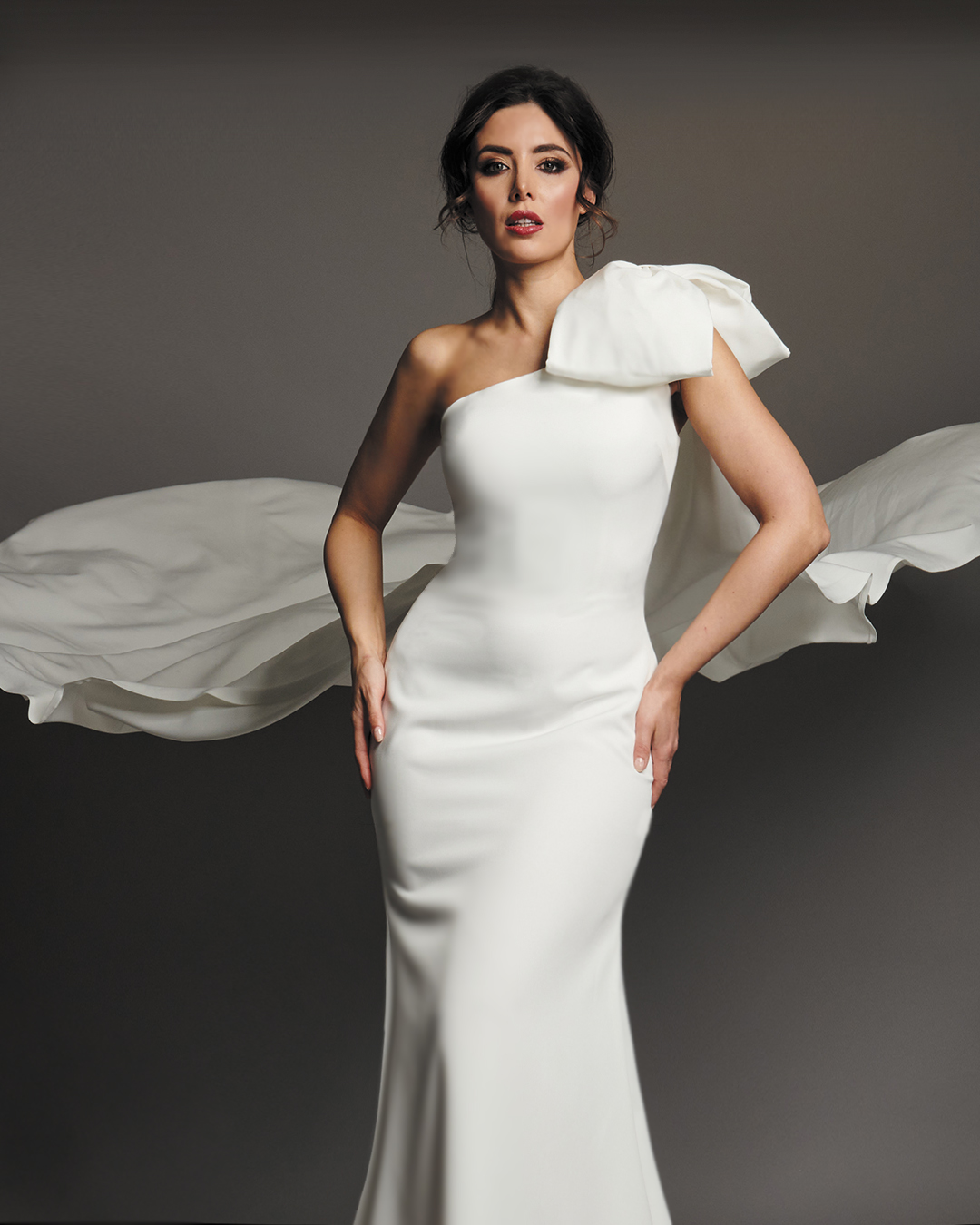 Arianna one shoulder crepe wedding dress, close view of sculpted bow and draped cape.