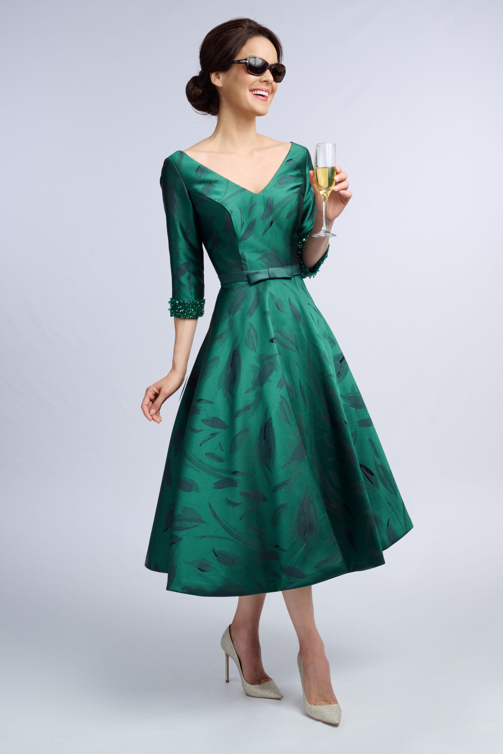 Model in the Epsom emerald green occasion dress with V neckline, beaded cuffs and full midi skirt