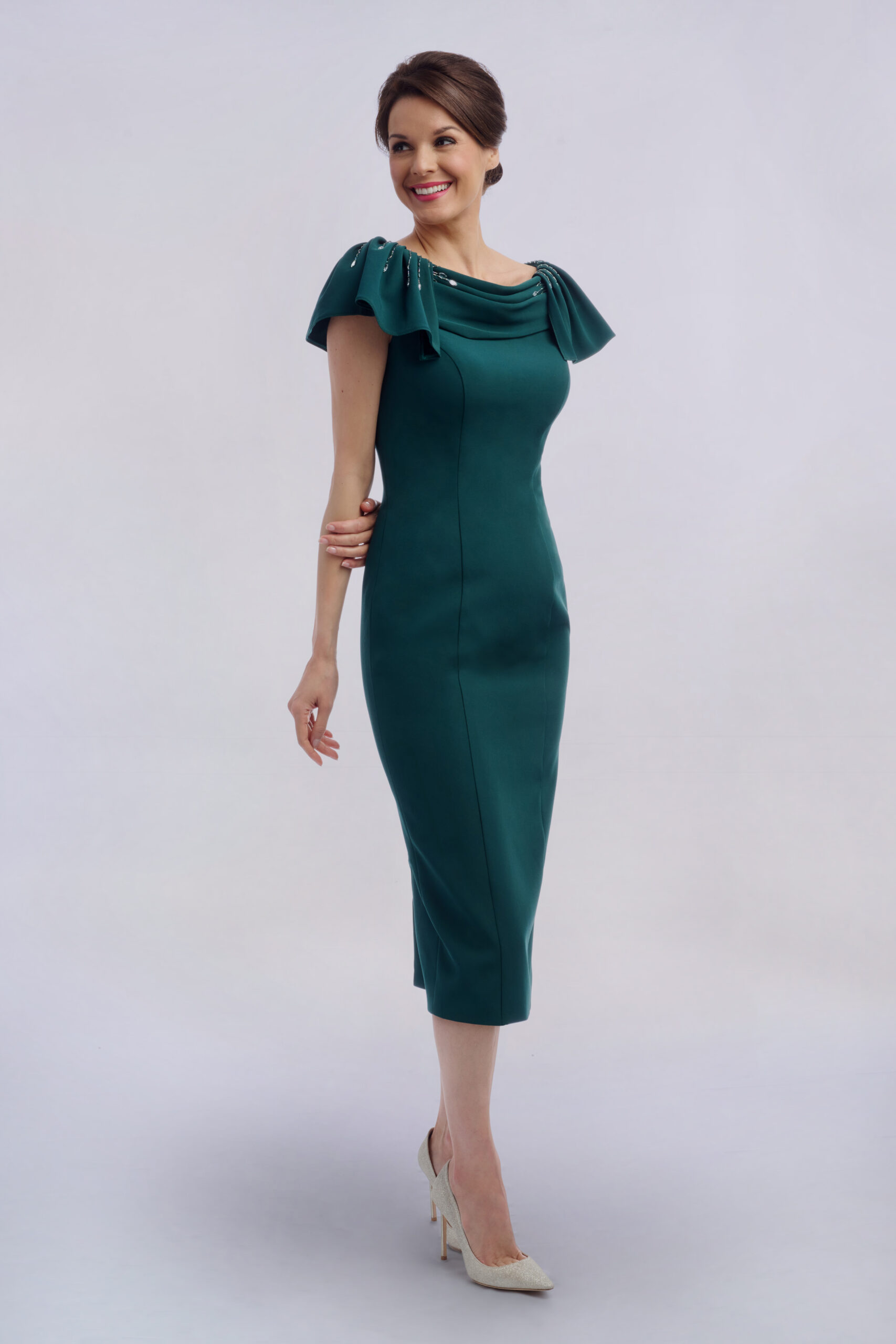 Model in the Opollo emerald green occasion dress with draped cowl collar, beaded shoulders and fitted midi skirt