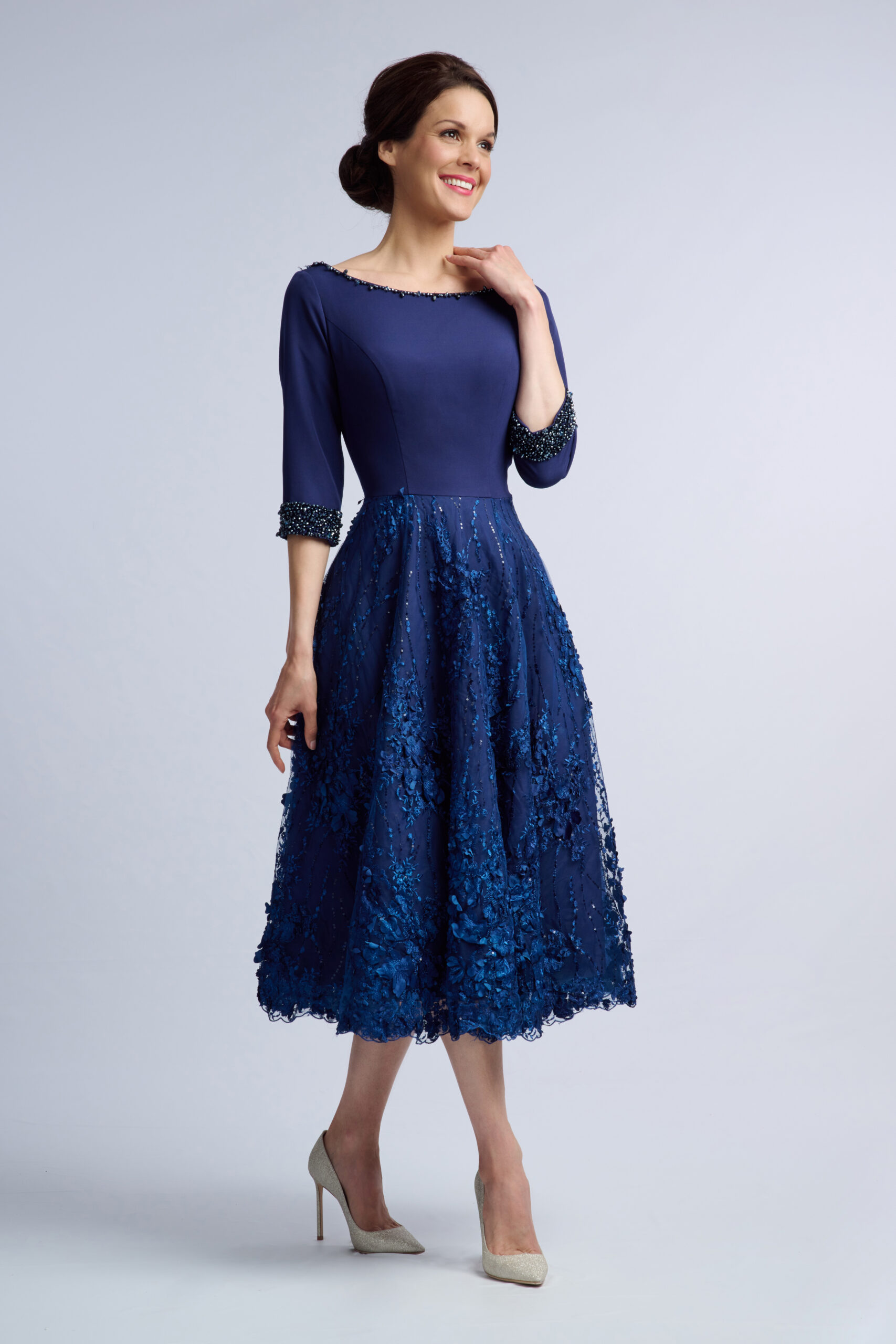 Model in the Islington navy occasion dress with beaded boat neckline, three-quarter sleeves and floral lace skirt