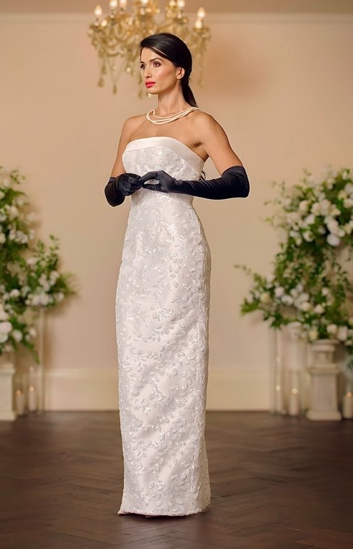 Front view of the Christina ivory column wedding dress with a strapless folded satin neckline and tonal floral embroidered lace covering the fitted skirt.
