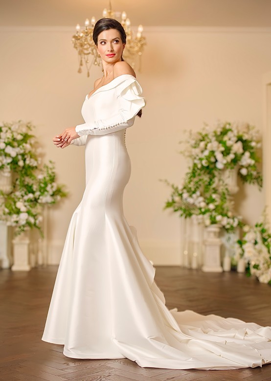 Back view of the Lyla ivory satin fit-and-flare wedding dress with a keyhole back, covered buttons, floral leaf appliqué and a full skirt flowing into a sweeping train.