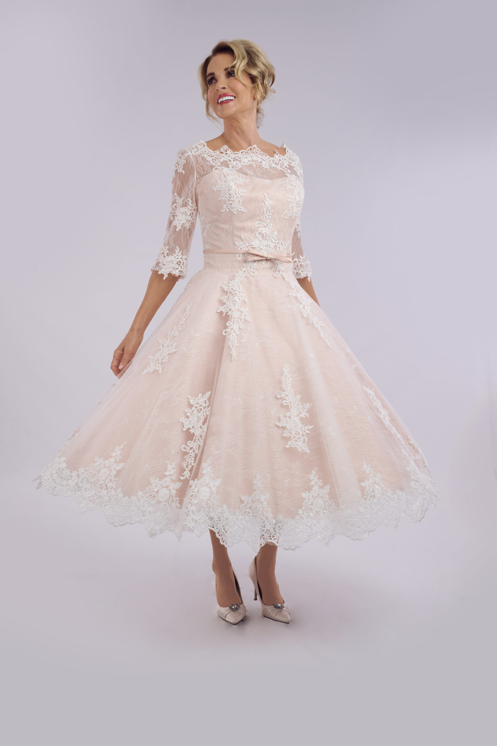 Amelia blush pink tea length wedding dress for older brides, with an ivory lace overlay and illusion sleeves