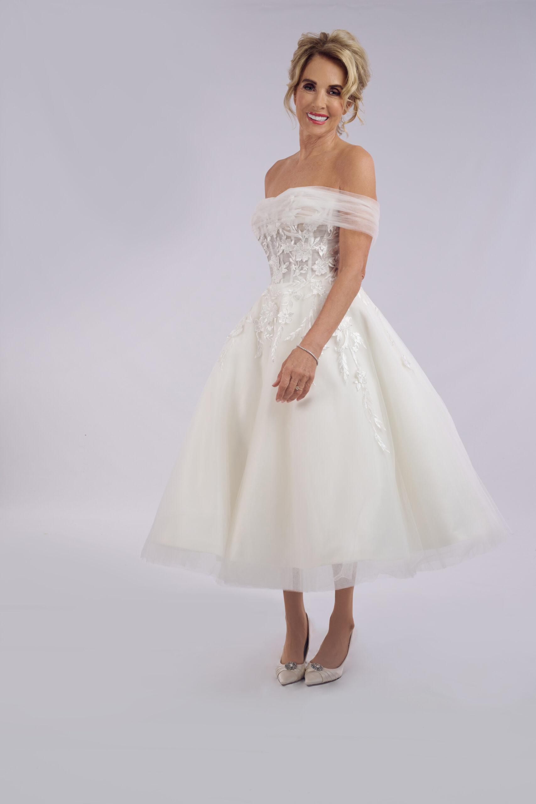 Mila off-the-shoulder tea length wedding dress for older brides, with a blush tulle neckline and floral lace bodice